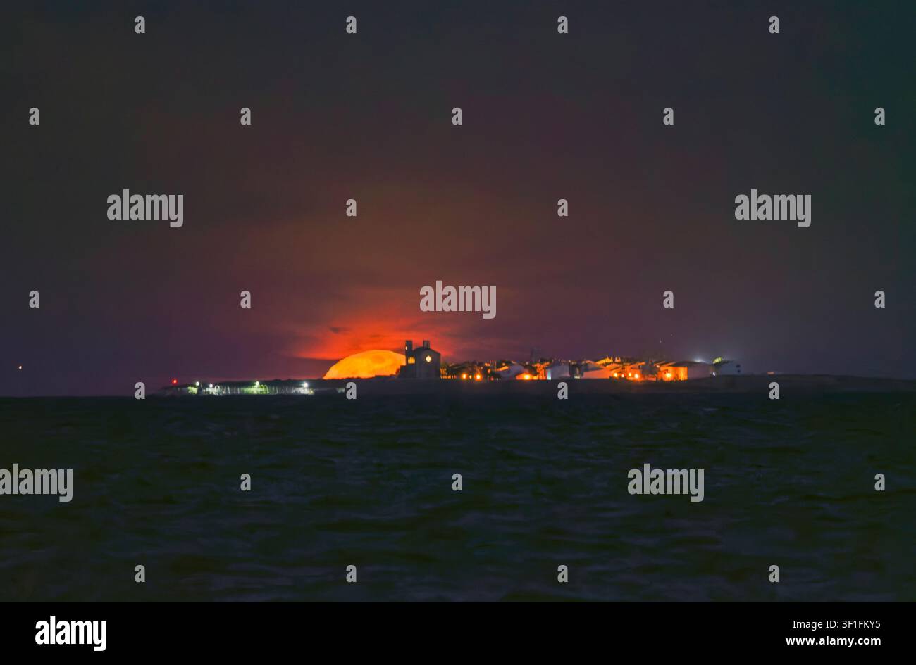 Atemberaubender riesiger orangefarbener Vollmond, der hinter der Insel Tabarca untergeht Stockfoto