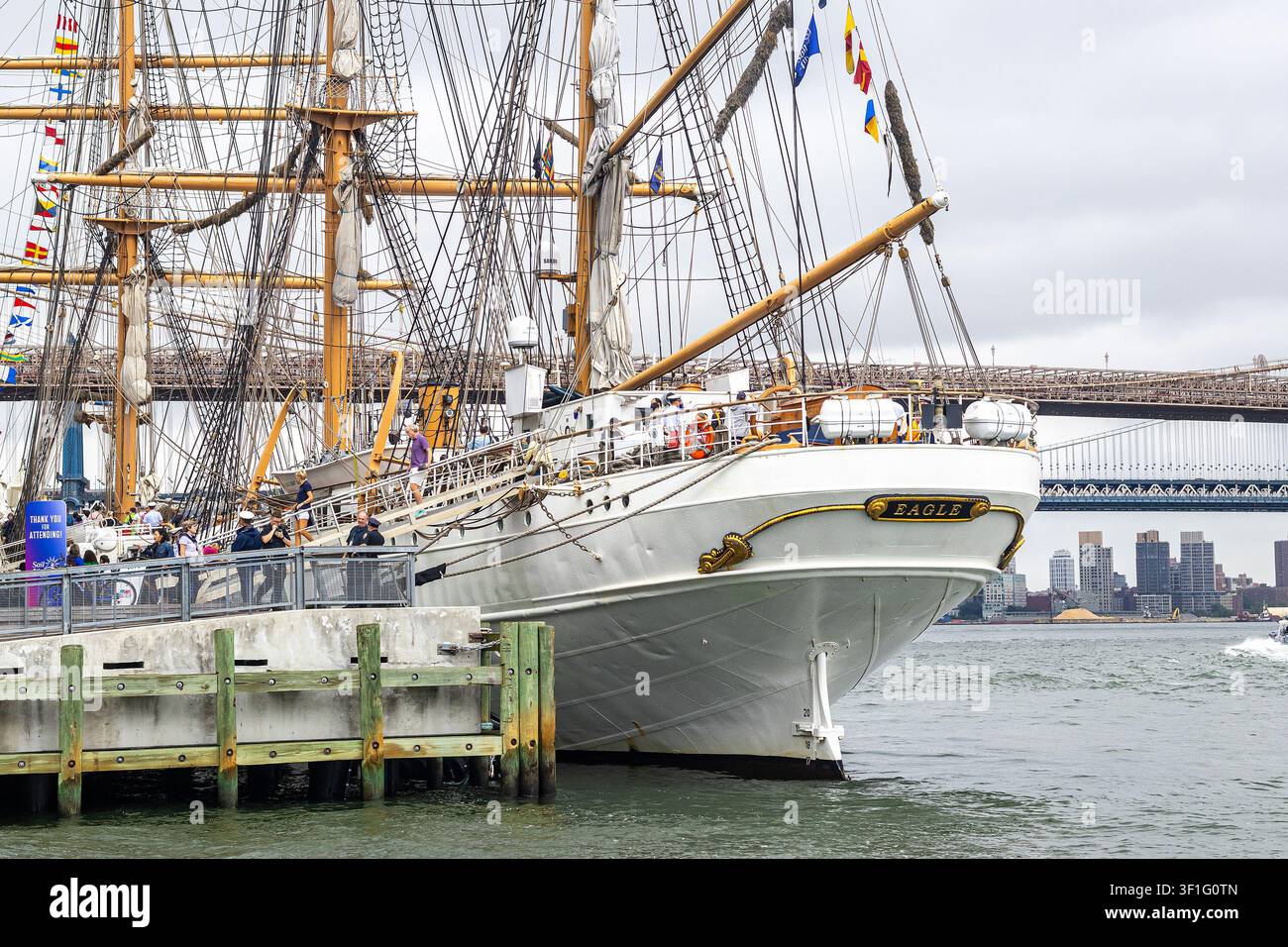 USCGC Eagle (Barque Eagle), Segelschiff der United States Coast Guard, das im South Street Seaport in Manhattan liegt, mit der Brooklyn Bridge im Hintergrund Stockfoto