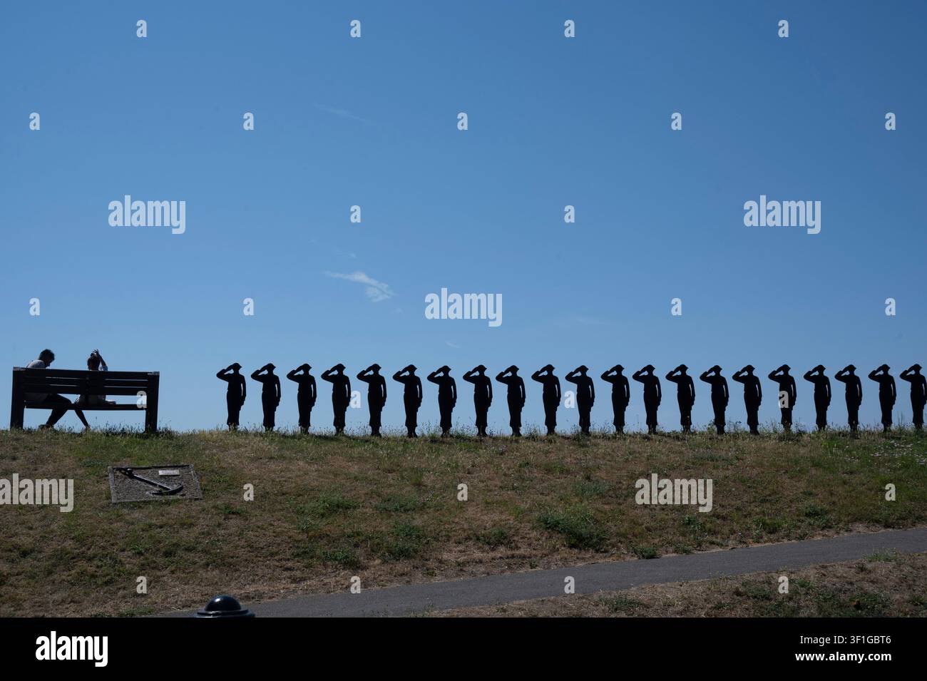 Purfleet, Essex. Vor dem Purfleet-Erbe- und Militärzentrum. Junges Paar auf einer Bank neben der Silhouette eines Soldaten als Denkmal für die Gefallenen des Ersten Weltkriegs Stockfoto