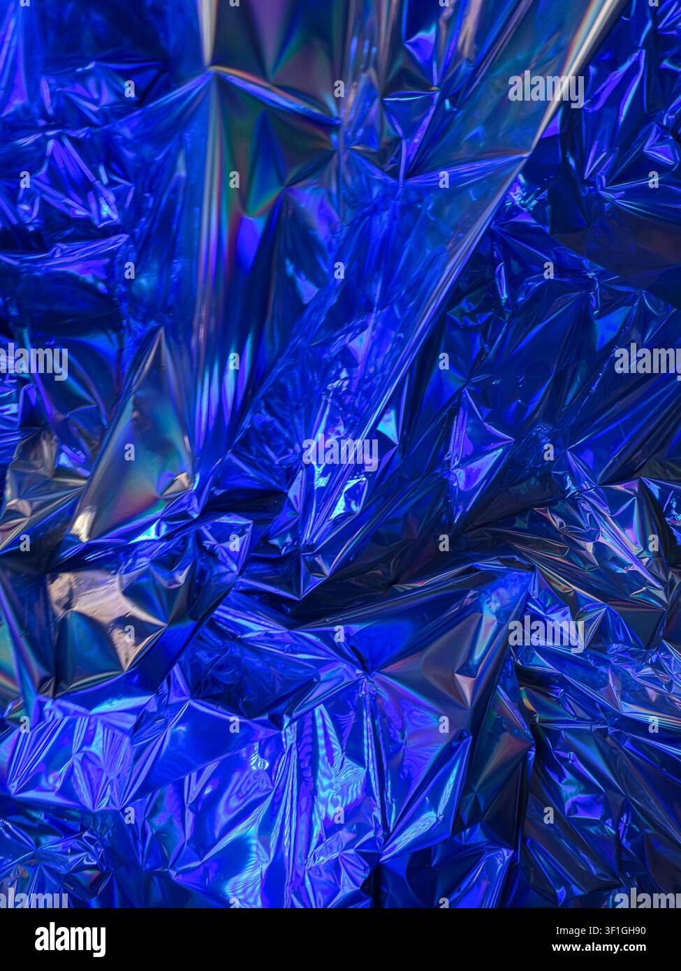 Abstrakte zerknitterte Metallfolienoberfläche mit lebhaften Blautönen und holografischen Reflexionen. Tiefe Schatten und helle Highlights erzeugen eine dramatische Textur Stockfoto