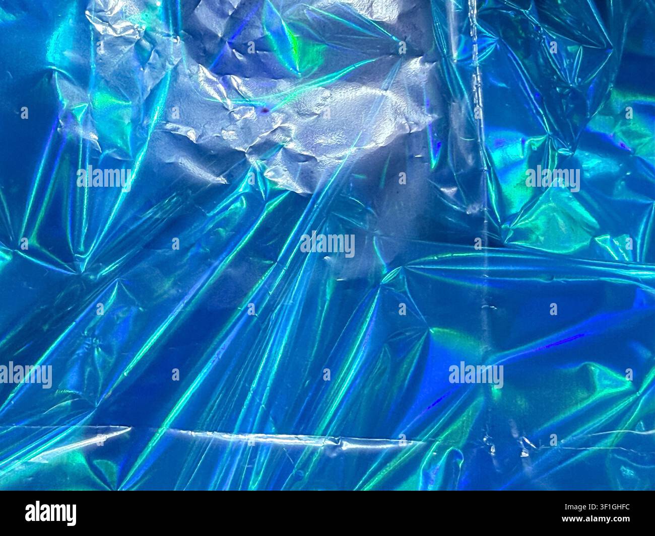 Abstrakte metallische blaue Oberfläche mit Falten und Furchen, die irisierende grüne und violette Highlights erzeugen. Lebendige und glänzende Textur geeignet für Futuri Stockfoto