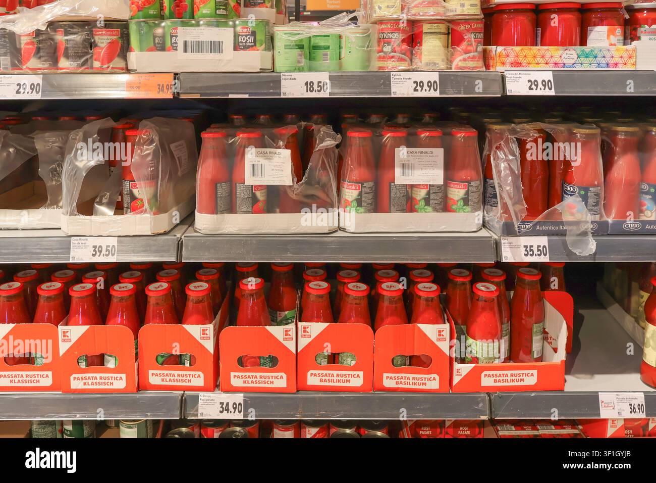 Regale mit Flaschen mit Tomatensoße und verpackten Lebensmitteln mit sichtbaren Handelsmarken und Preisschildern in einem Supermarkt – Chișinău Stockfoto