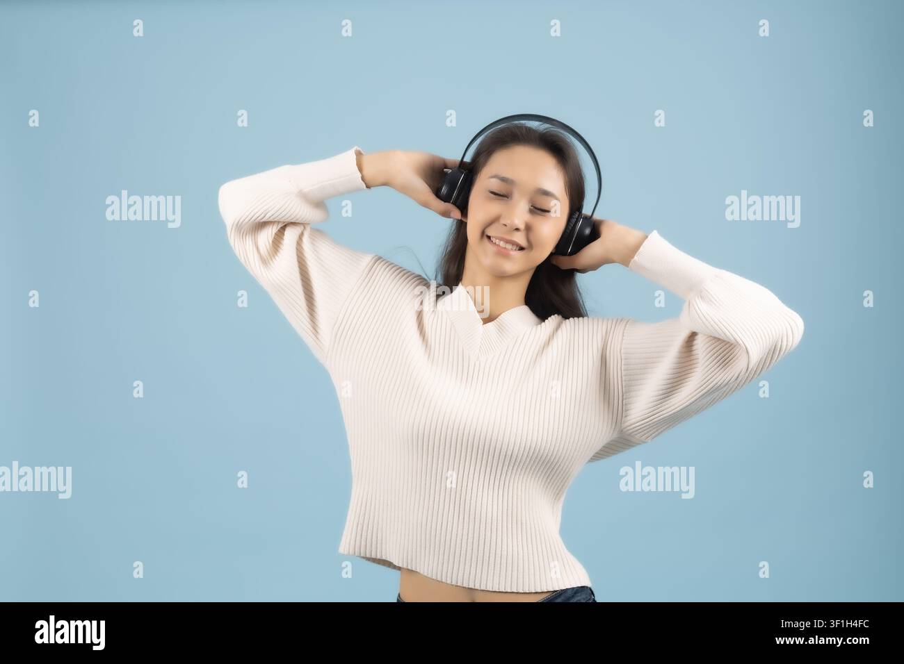 Junge Frau hört Musik mit kabellosem Kopfhörergerät Stockfoto