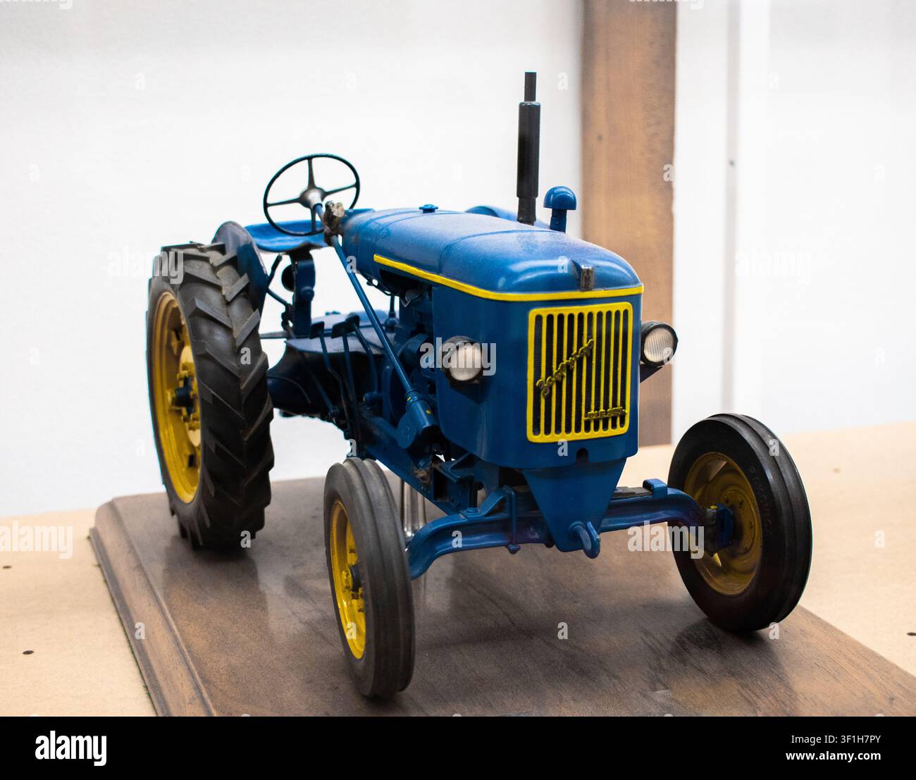 Nahaufnahme eines blauen Traktors mit gelben Details, der seine landwirtschaftlichen Maschinen, mechanischen Komponenten und sein robustes Design hervorhebt. Ländliche Landwirtschaft und mo Stockfoto
