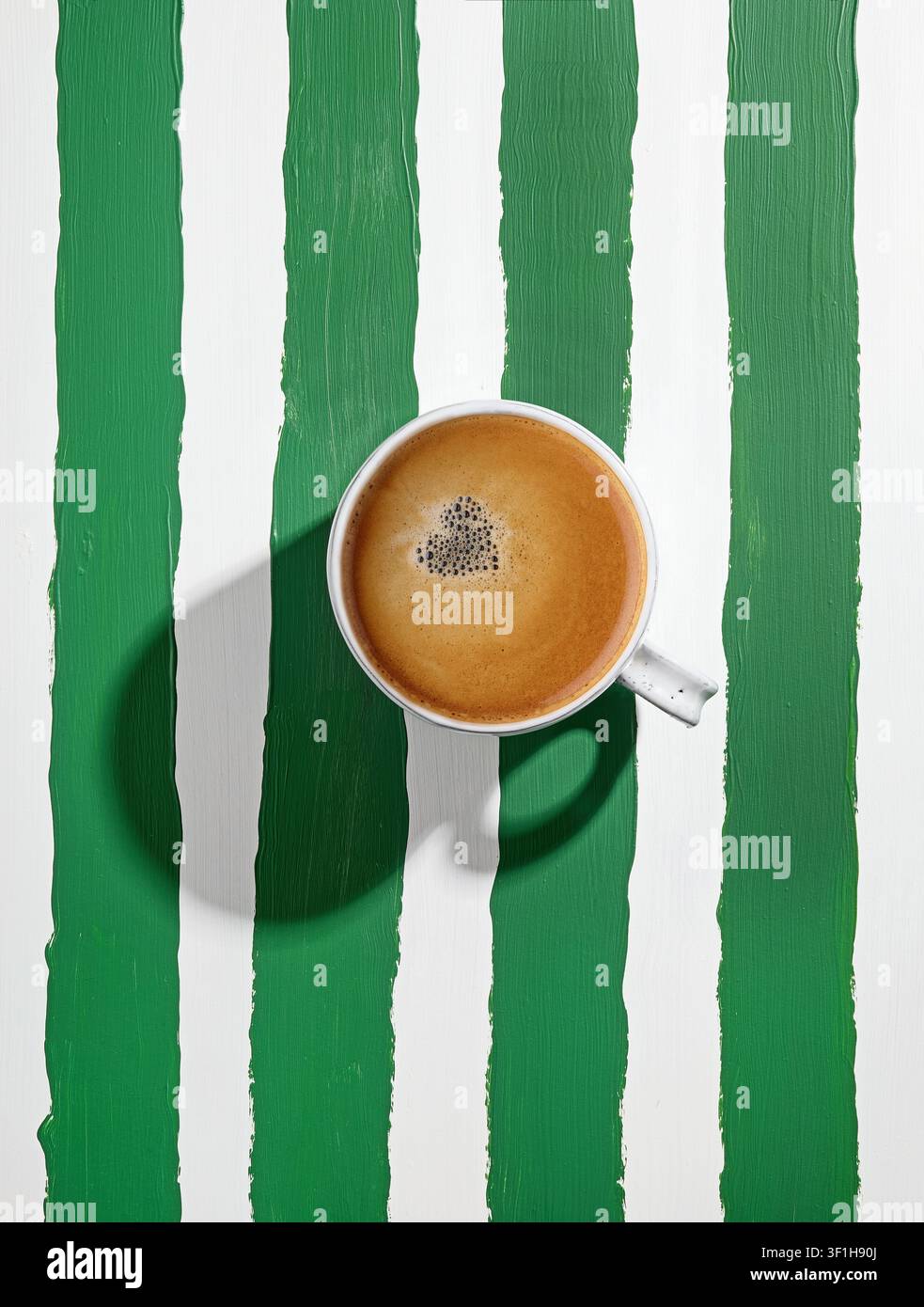 weiße Keramik-Espresso-Kaffeetasse auf gestreiftem Tisch in Grün und Weiß, Blick von oben Stockfoto