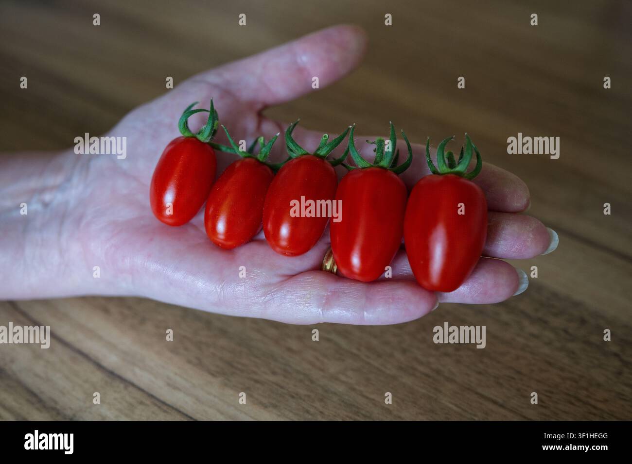 Frau hält rote Tomaten über eine Küchentheke Stockfoto