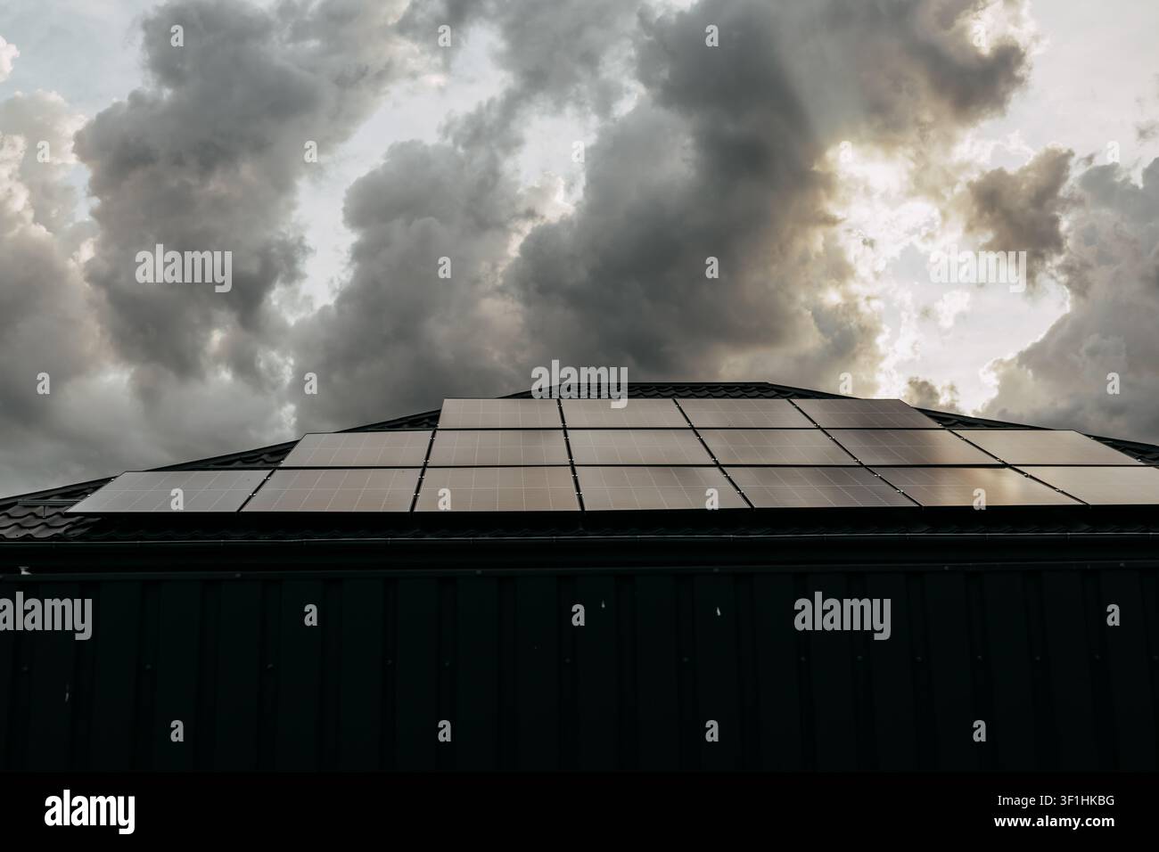 Dachsolarmodule auf einem modernen Wohnhaus unter dramatischen Gewitterwolken, die erneuerbare Energien und nachhaltiges Li veranschaulichen Stockfoto
