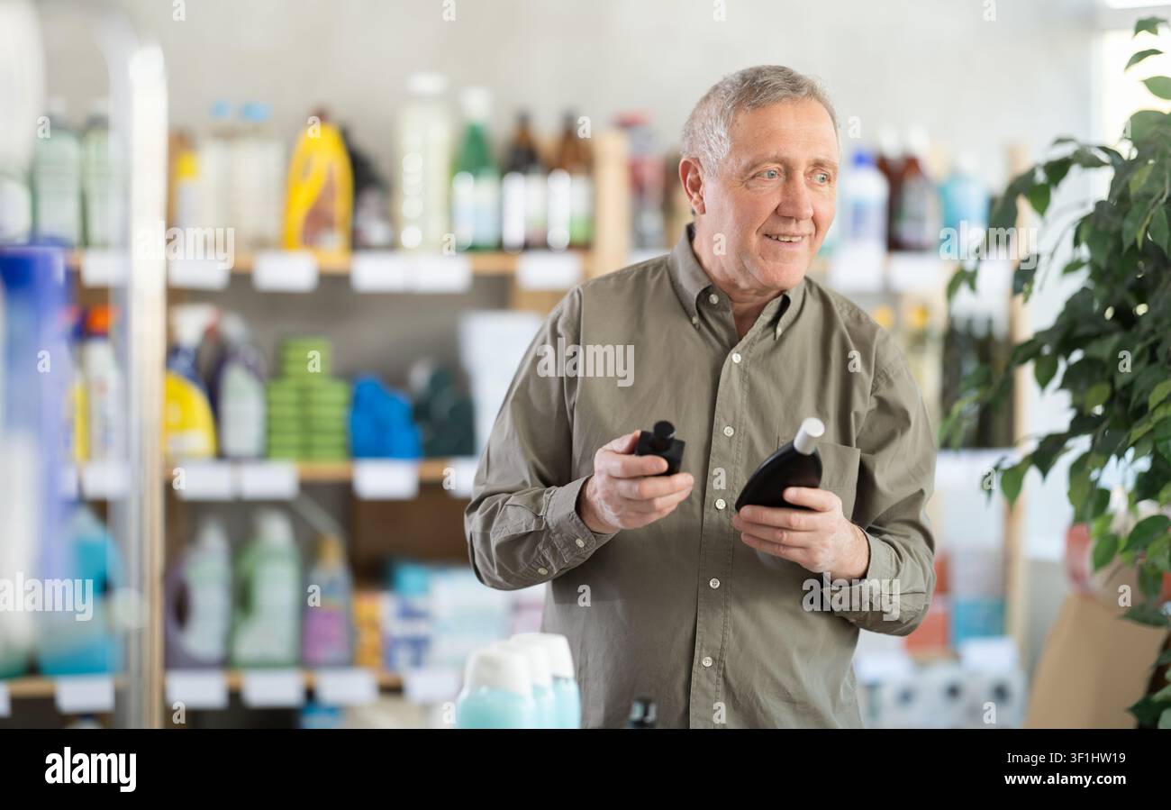 Senior man schnüffelt Duft von Parfüm, wählt Duftspray mit angenehmem Geruch Stockfoto