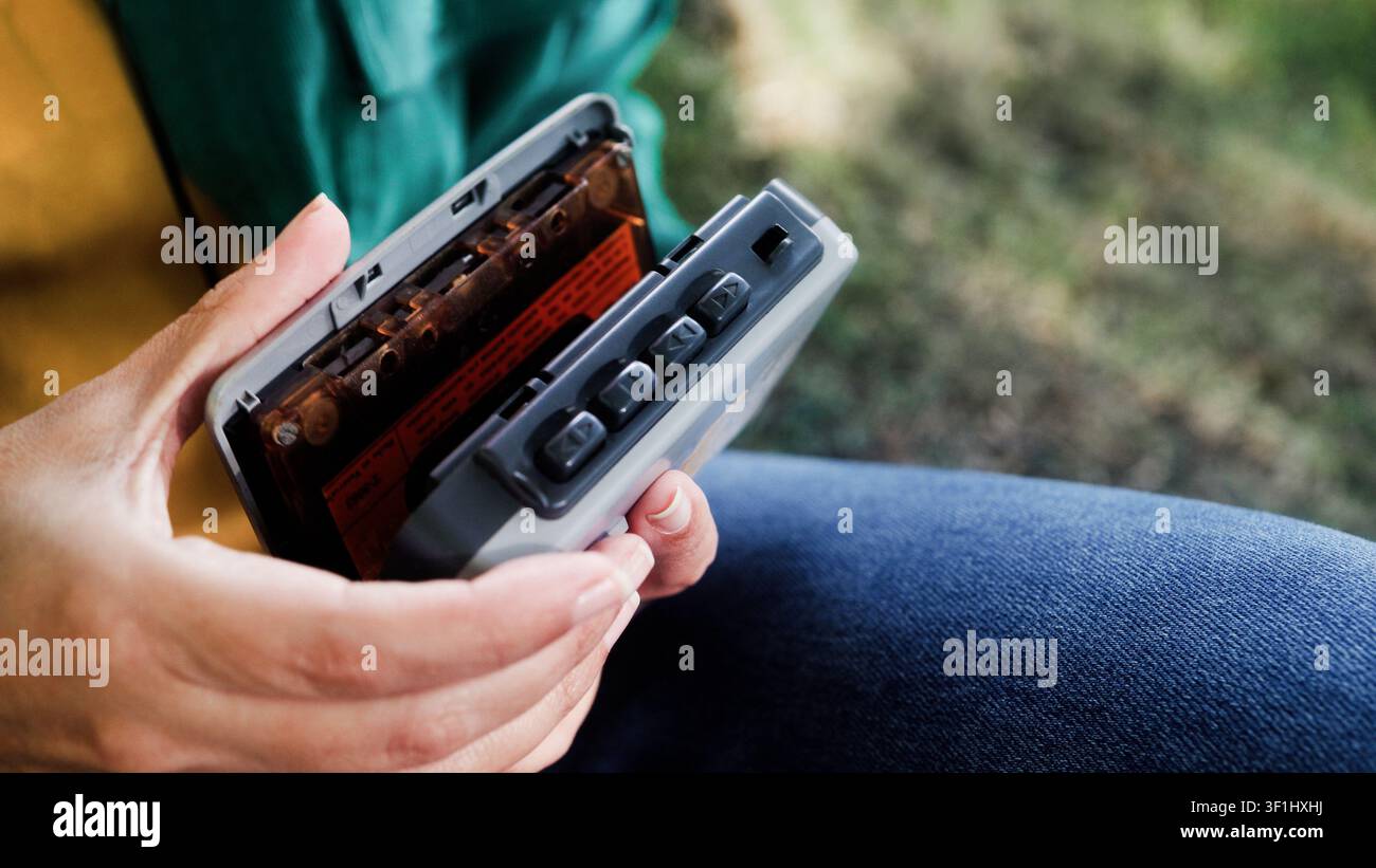 Person, die eine Kassette in einen tragbaren Player im Freien einlegt - Retro-Audio- und Nostalgie-Lebensstiltrend Stockfoto