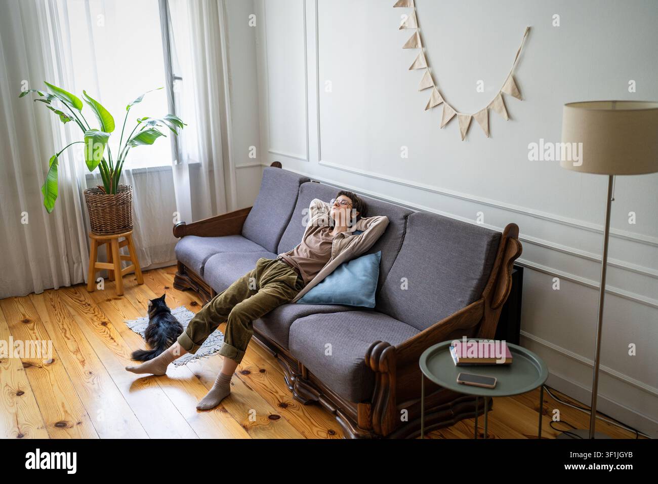 Träumige faule Frau verbringt einen langweiligen Tag zu Hause, entspannt auf dem Sofa, Wochenendprokrastination und Erholung. Stockfoto