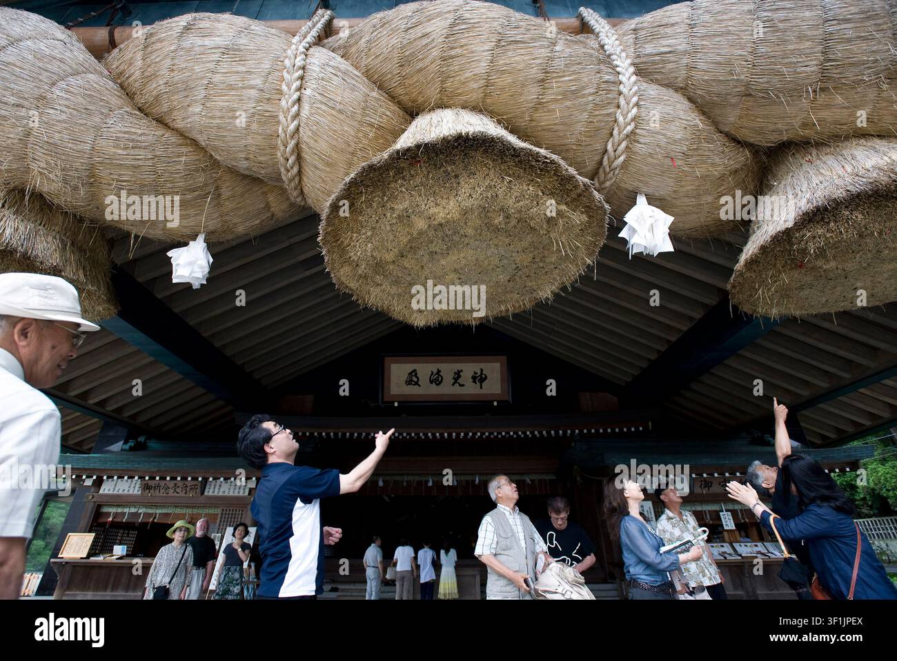 Besucher versuchen, Münzen in das Shimenawa (heiliges Strohseil) des Kagura-Den-Saals des Izumo-Taisha-Schreins in Izumo, Präfektur Shimane, zu werfen Stockfoto