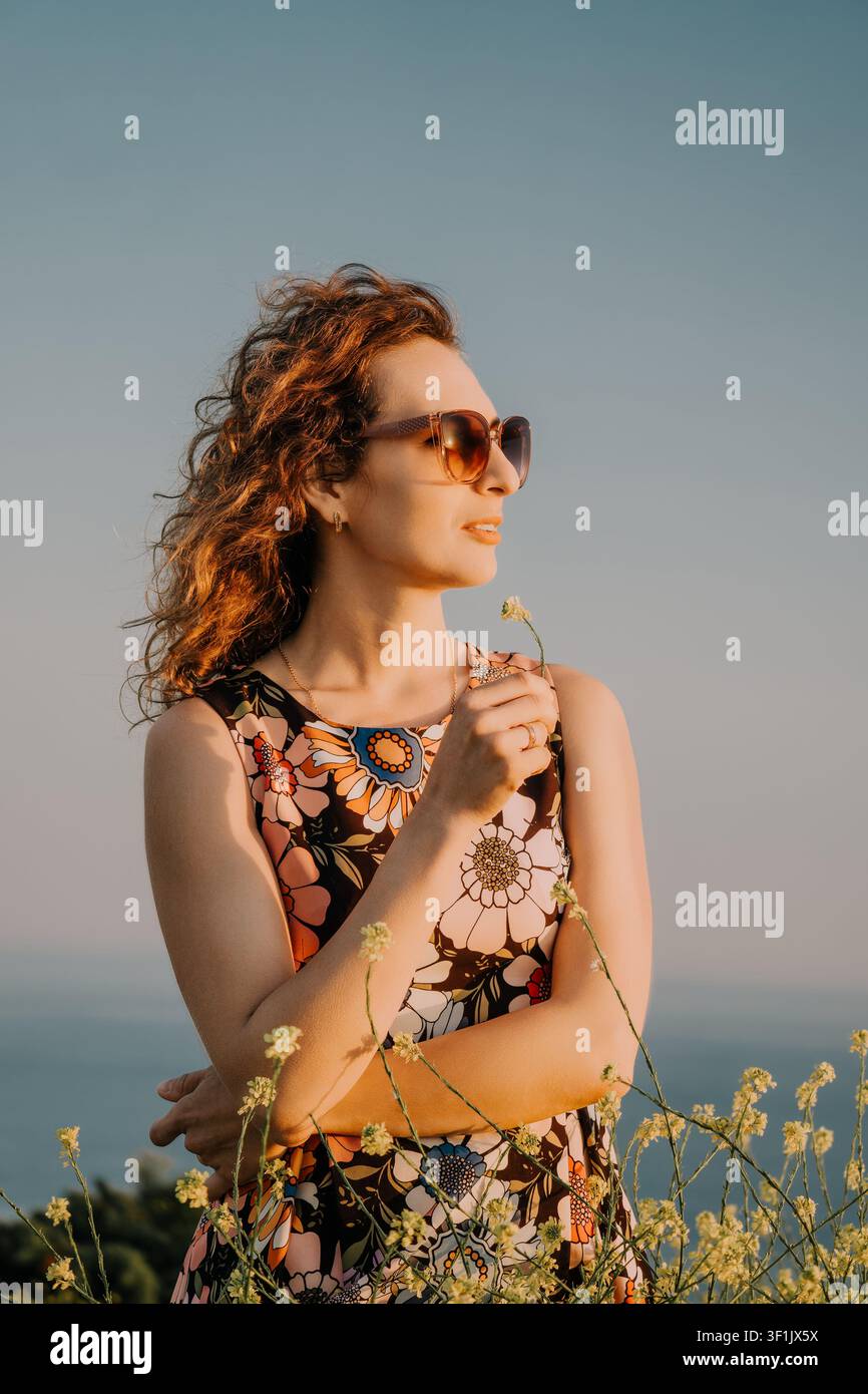Frau Blumen Sonnenuntergang, junge Frau hält eine kleine Wildblume im Freien bei Sonnenuntergang mit Kopierraum für inspirierende Konzepte und Branding Stockfoto