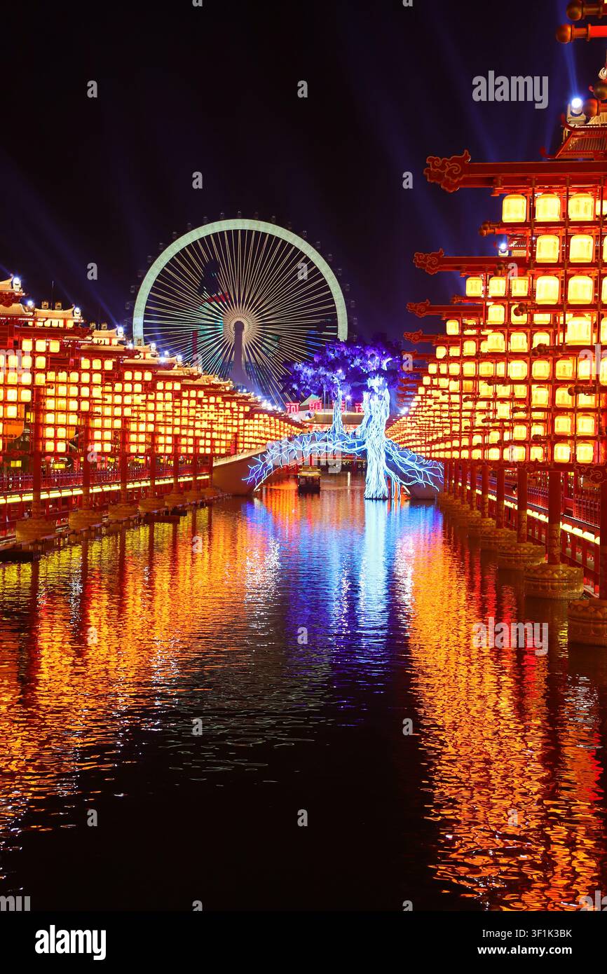 Eine atemberaubende Nachtszene in der Tangshan Hetou Old Street, wo sich ein leuchtendes Riesenrad hinter symmetrischen, mehrstöckigen traditionellen chinesischen Gebäuden erhebt Stockfoto