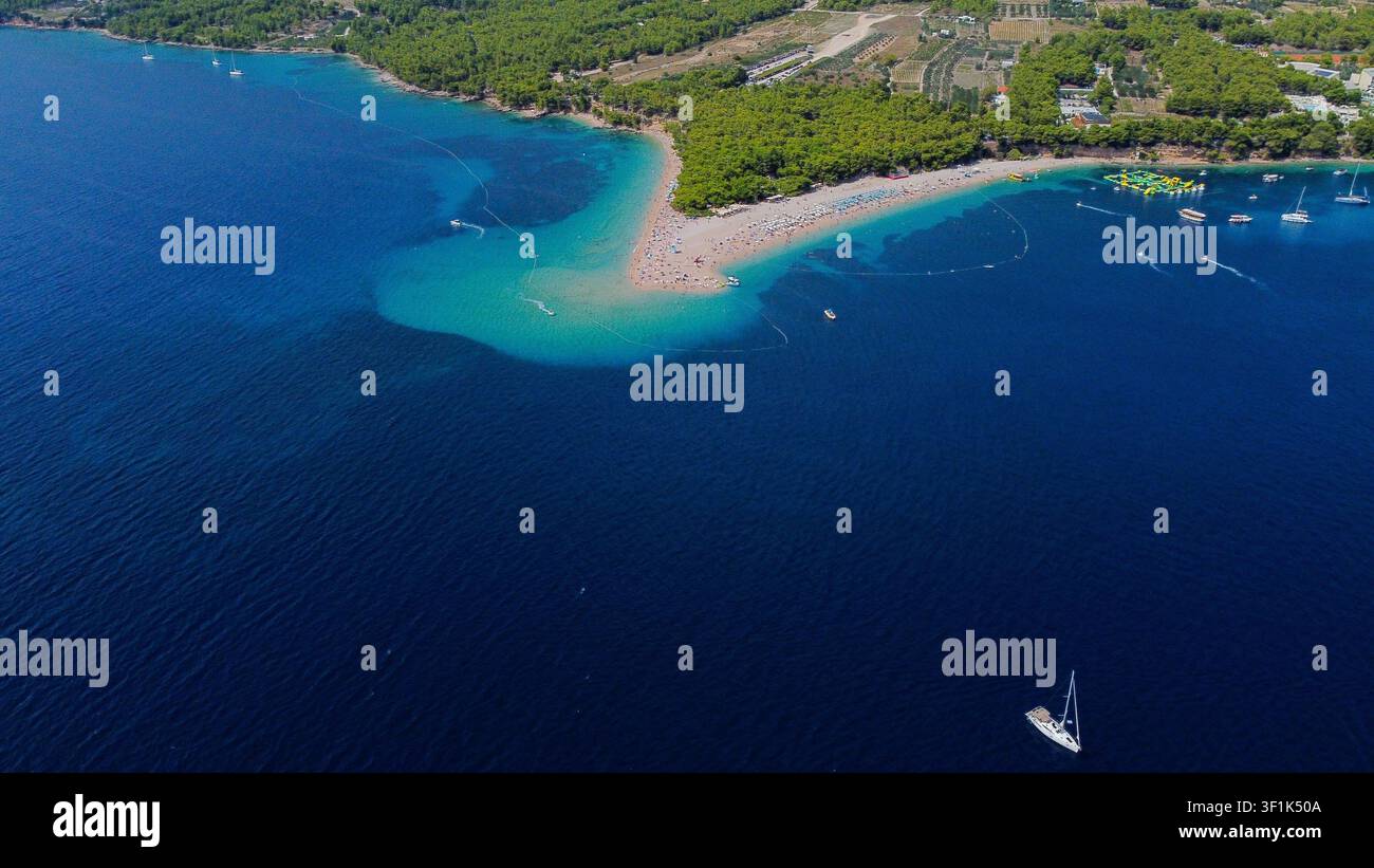 Zlatni rat Strand im Sommer, eine ikonische Kieselformation, die sich unter klarem Himmel in das tiefe blaue Adriatische Meer erstreckt Stockfoto