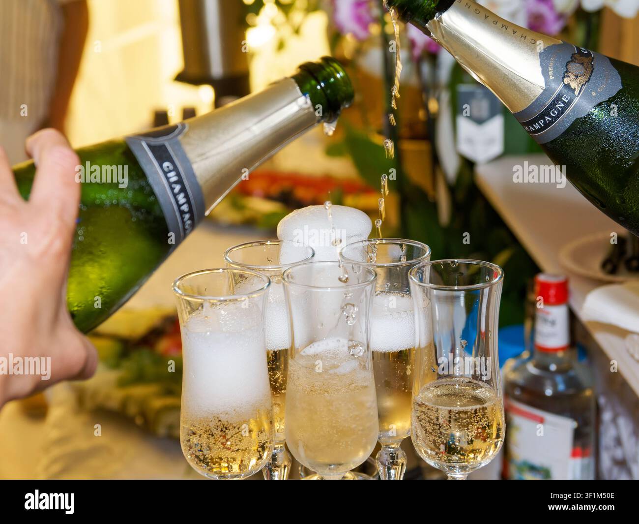 Schaumwein wird bei einer Hochzeitsfeier in Sektgläser gegossen Stockfoto