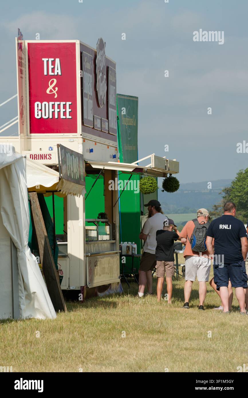 Menschen, die für Tee und Kaffee Schlange stehen. Die englische Art, darauf zu warten, bedient zu werden. Bilden Sie eine Schlange! Stockfoto