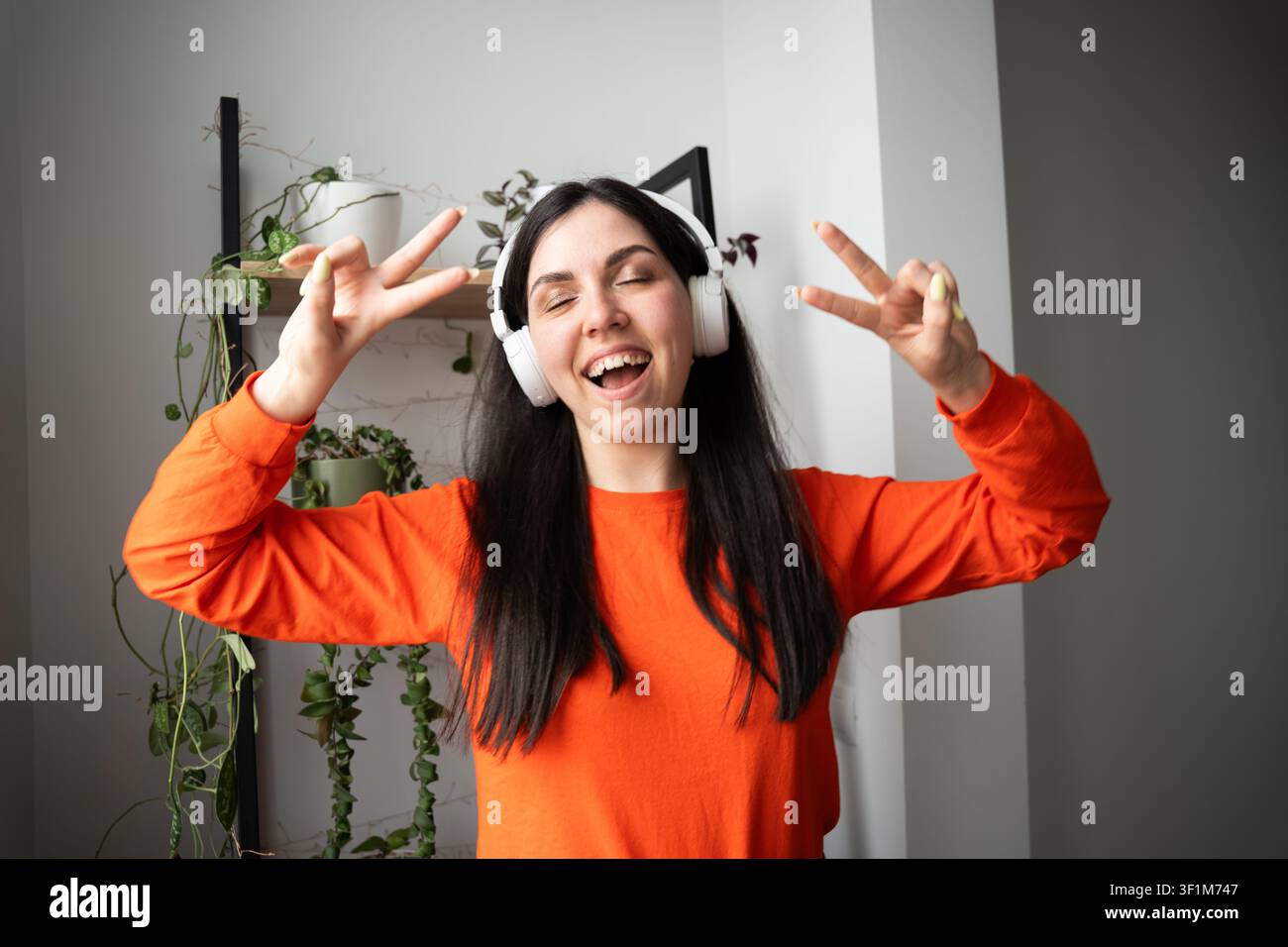 Junge Frau genießt Musik mit kabellosen Kopfhörern im Innenraum. Musik-Streaming, Online-Unterhaltung und positiver Lebensstil. Stockfoto