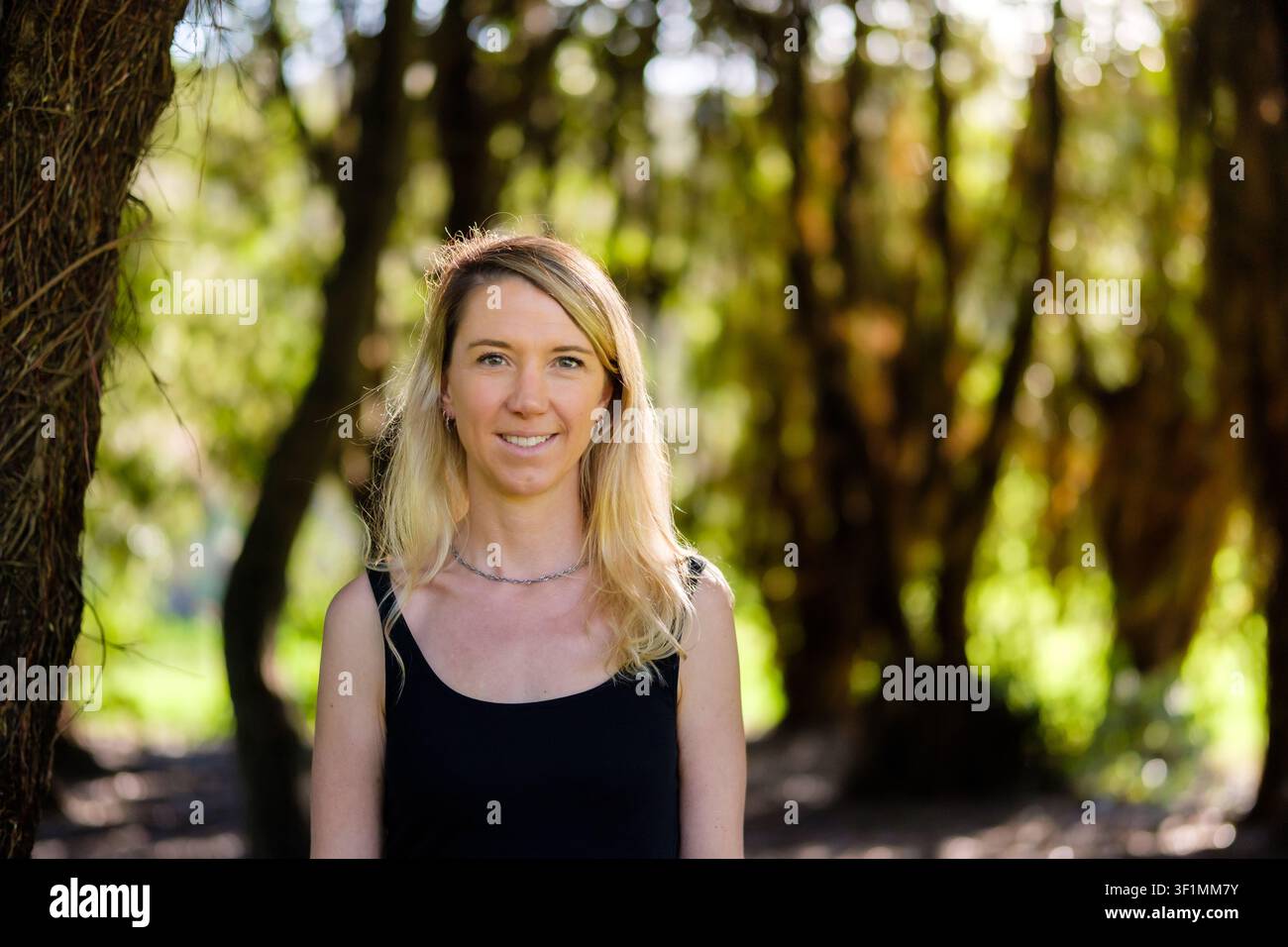 Junge blonde Frau lächelt im Naturwaldporträt Stockfoto