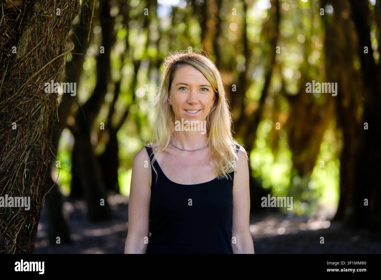 Frau steht in einer grünen Waldumgebung und zeigt natürliche Schönheit und Ruhe Stockfoto