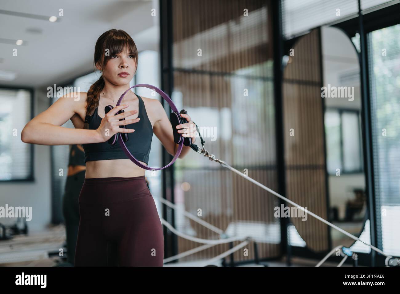 Junge Frau macht Pilates-Ring-Training mit Widerstandsbändern in einem modernen Fitnessstudio Stockfoto