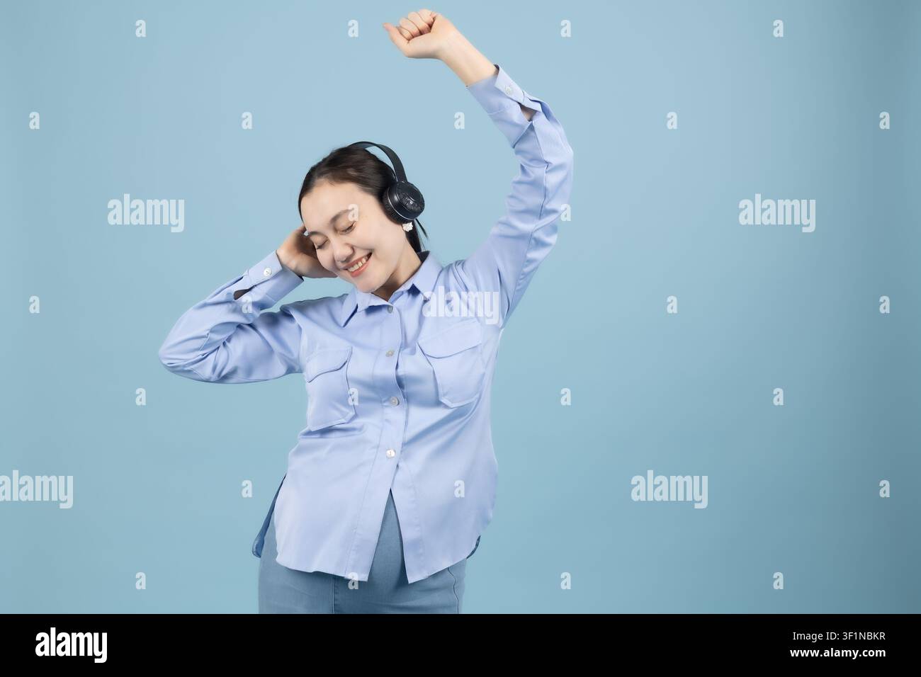 Fröhliche junge Frau mit Kopfhörern, die zu ihrer Lieblingsmusik in der St... tanzt Stockfoto