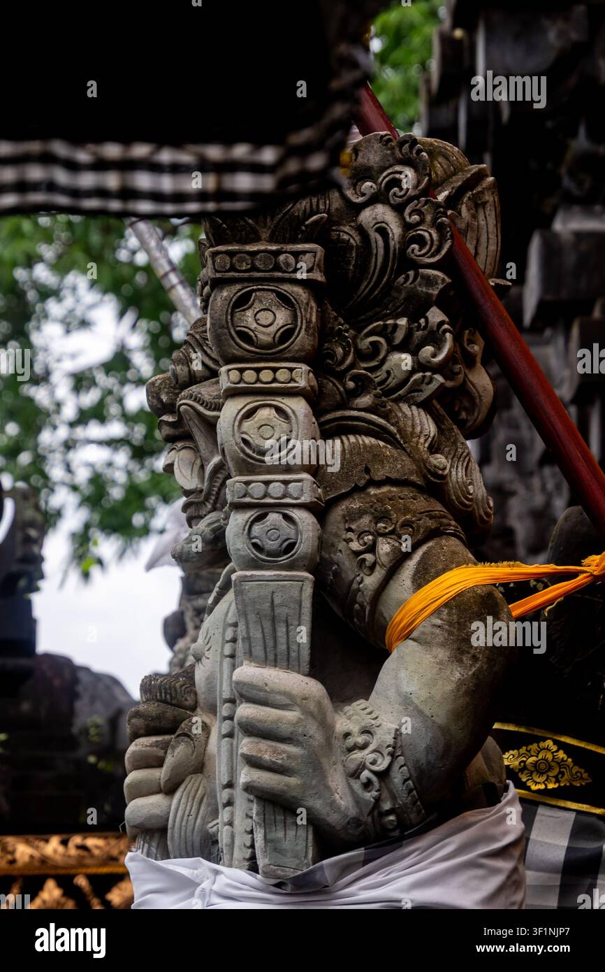 Nahaufnahme einer geschnitzten steinernen Wächterstatue an einem Tempel, in weißes und gelbes Tuch gehüllt, mit reichen Details, weichem Tageslicht und einer ruhigen spirituellen Stimmung Stockfoto