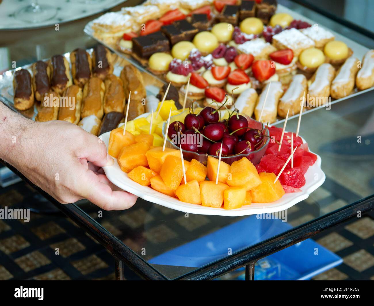 Frisches Obsttablett mit Kirschen und Melone, serviert mit verschiedenen Gebäckstücken bei einem Empfang Stockfoto