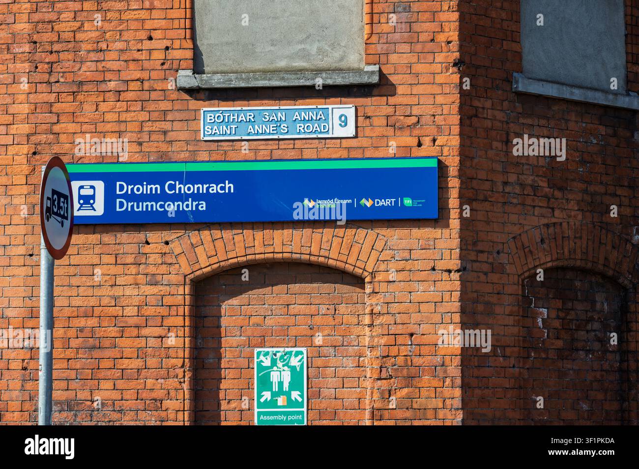 Nahaufnahme des Schildes des Bahnhofs Drumcondra und eines klassischen blauen Dubliner Straßenschildes an einer rotbacksteinernen Fassade. Stockfoto