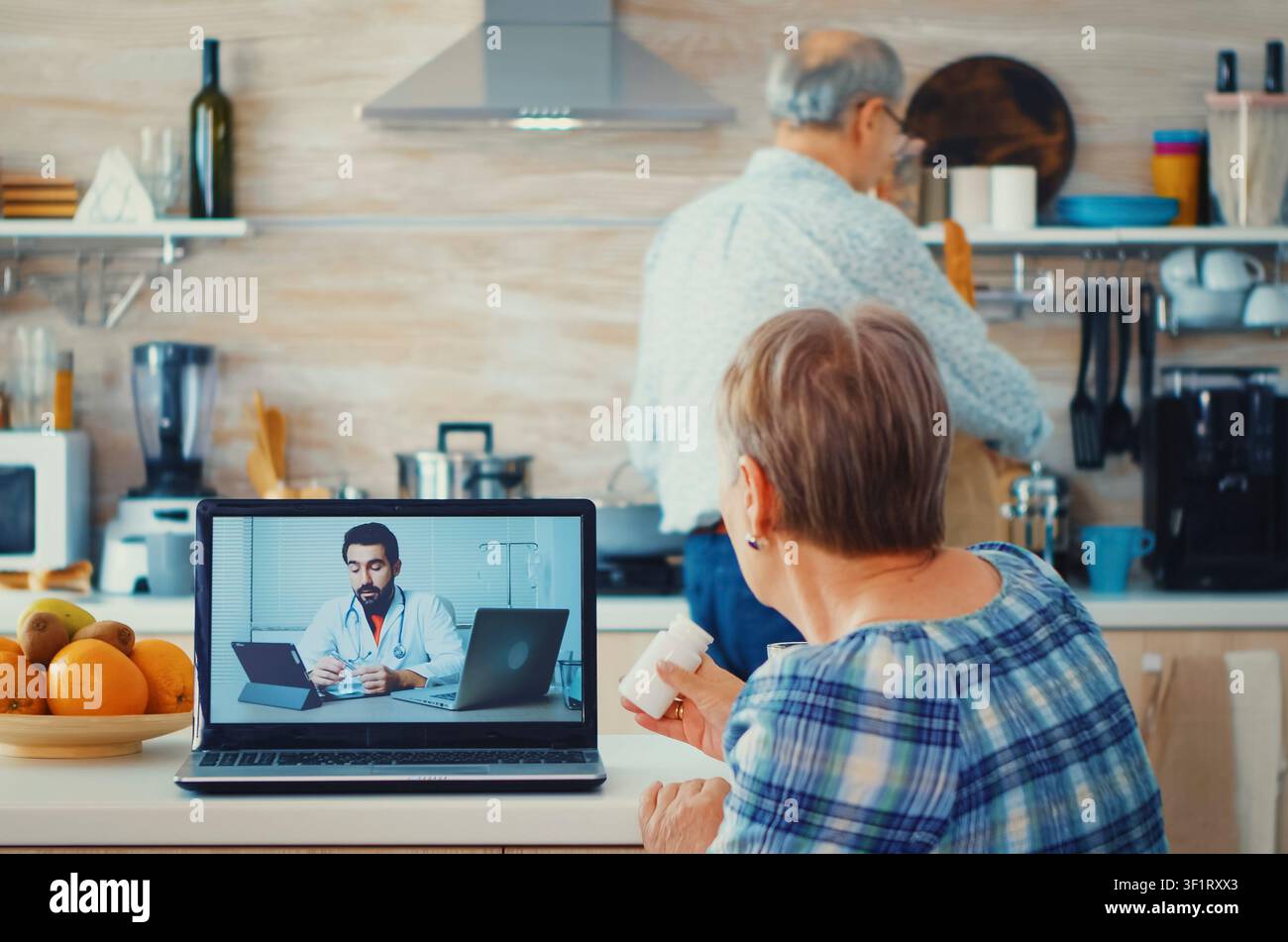 Pfleger hält eine Pillenflasche für einen älteren Patienten während der Klinikberatung, während er Online-Rezepte durchstöbert, Nachrichten liest und ein entspanntes Frühstück zu Hause teilt. Stockfoto