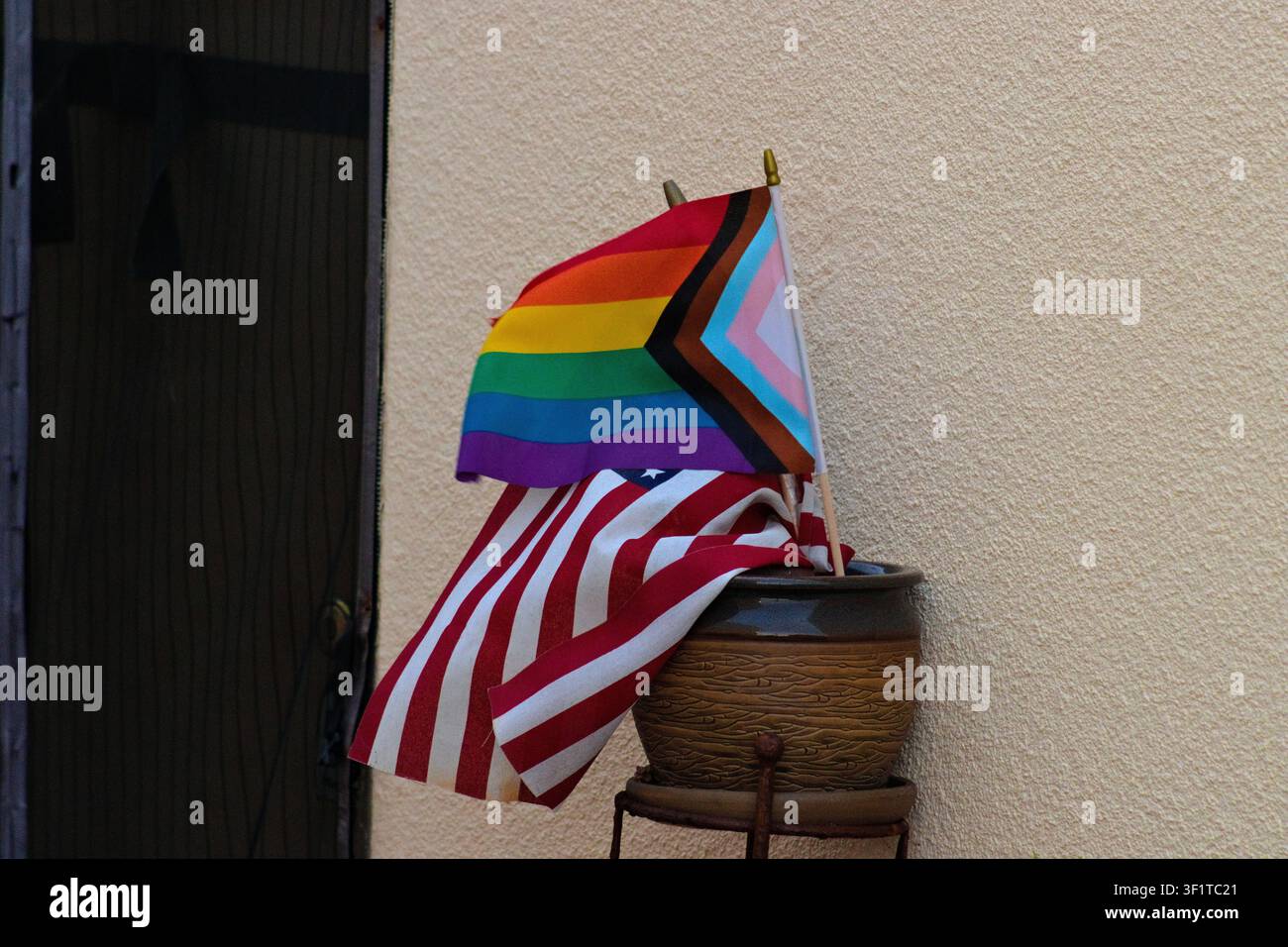 Progress Pride Flagge und amerikanische Flagge vor einem Wohngebäude Stockfoto