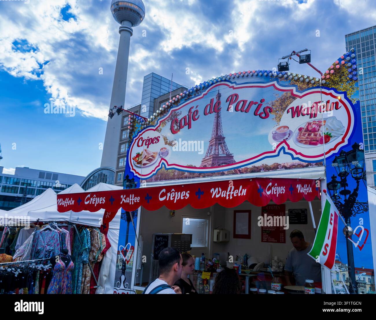 Ein französisch inspirierter Imbissstand „Café de Paris“ mit Crêpes und Waffeln steht am Alexanderplatz mit dem Berliner Fernsehturm im Hintergrund. Stockfoto