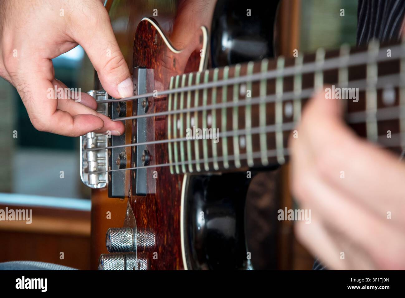 Kreative Nahaufnahme von Händen, die eine E-Bassgitarre spielen, die die Emotion und Handwerkskunst hinter Live-Musikaufführungen und Kunstfertigkeit einfangen Stockfoto