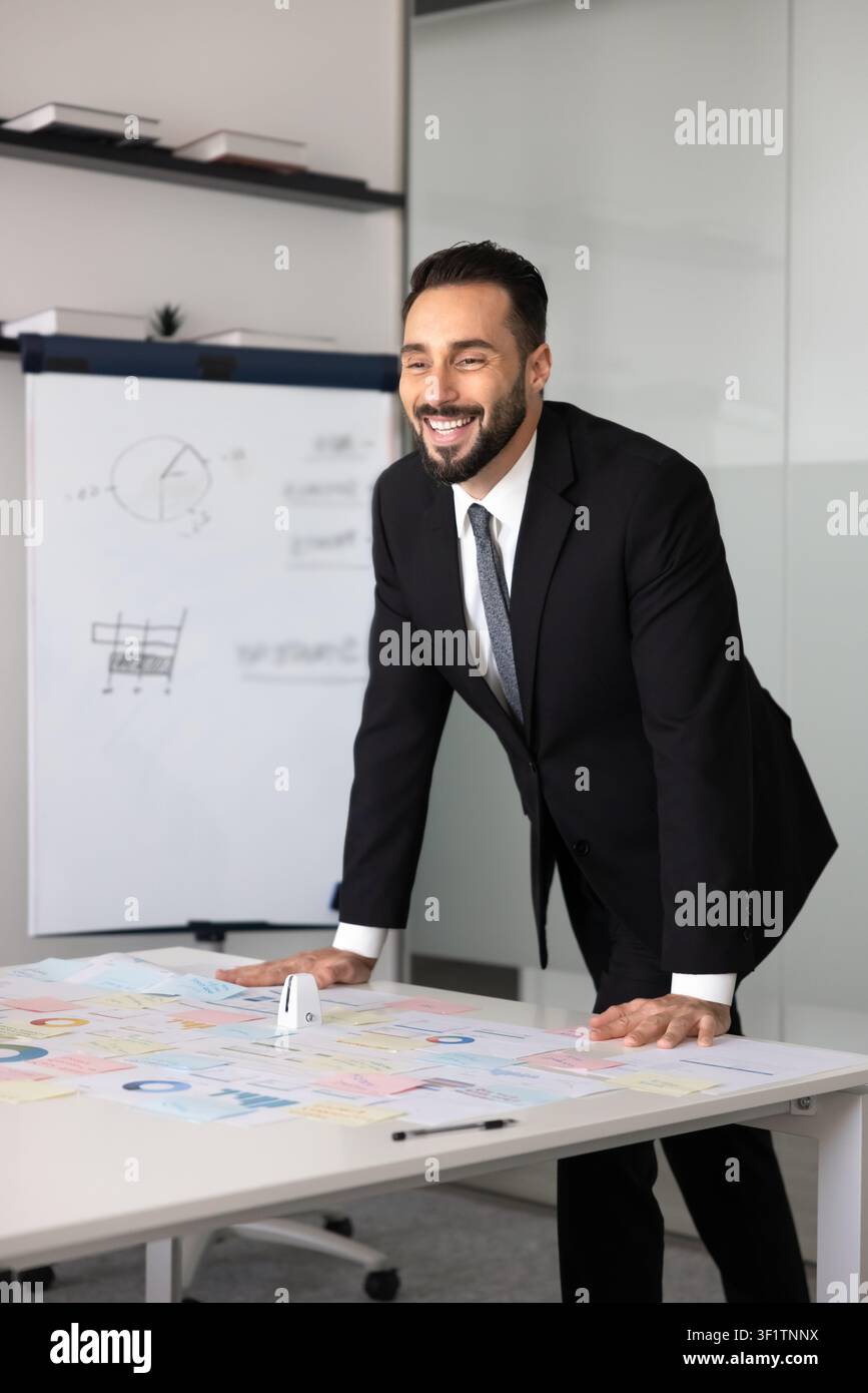 Geschäftsmann steht an einem Konferenztisch mit Verkaufsstatistiken in Diagrammen Stockfoto