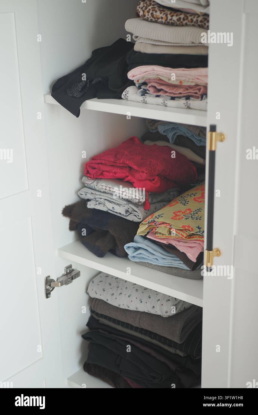 Ordentlich angeordnete Kleidung in einem Schrankgestell während des Tages Stockfoto