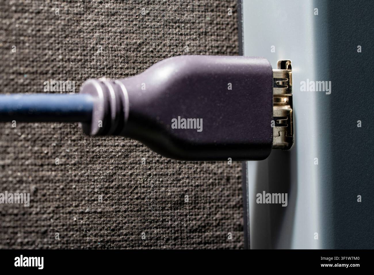 DisplayPort-Kabel, das in den Geräteanschluss eingesteckt ist, Nahaufnahme. Makroaufnahme eines schwarzen digitalen Interface-Kabels, das an einen elektronischen Geräteanschluss angeschlossen ist. Konzept von Datenübertragung Stockfoto