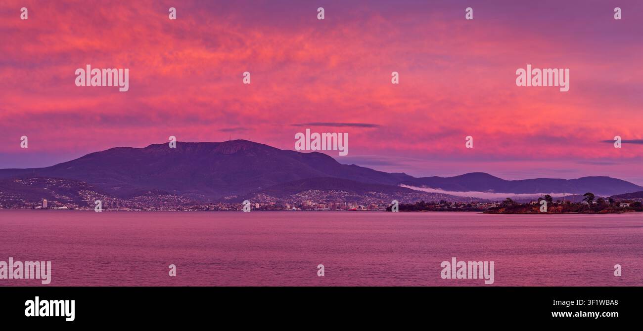 Panorama des Mount-Wellington-Gebirges und der Stadt Hobart unter einem rosa Morgenhimmel mit leichter Bewölkung, Tasmanien, Australien Stockfoto