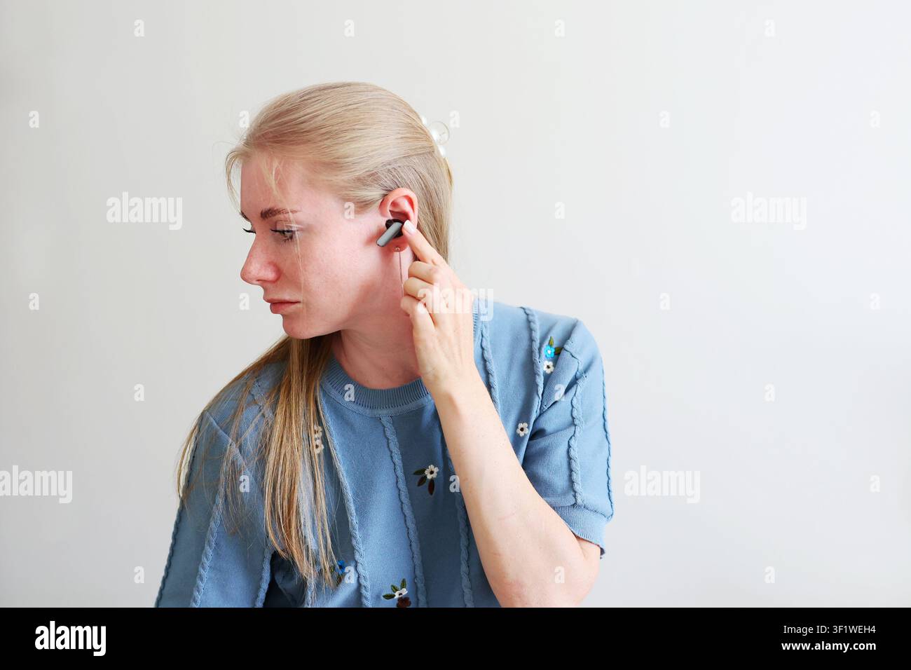 Junge Frau genießt ein kabelloses Audiogerät, schaut nach oben mit Kopierraum für Technologie- und Lifestyle-Werbung. Stockfoto