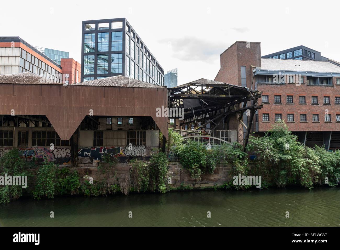 Alte verfallene Gebäude neben dem Fluss Irwell in der Nähe des Spinningfields-Gebiets der Stadt Manchester, England. Stockfoto