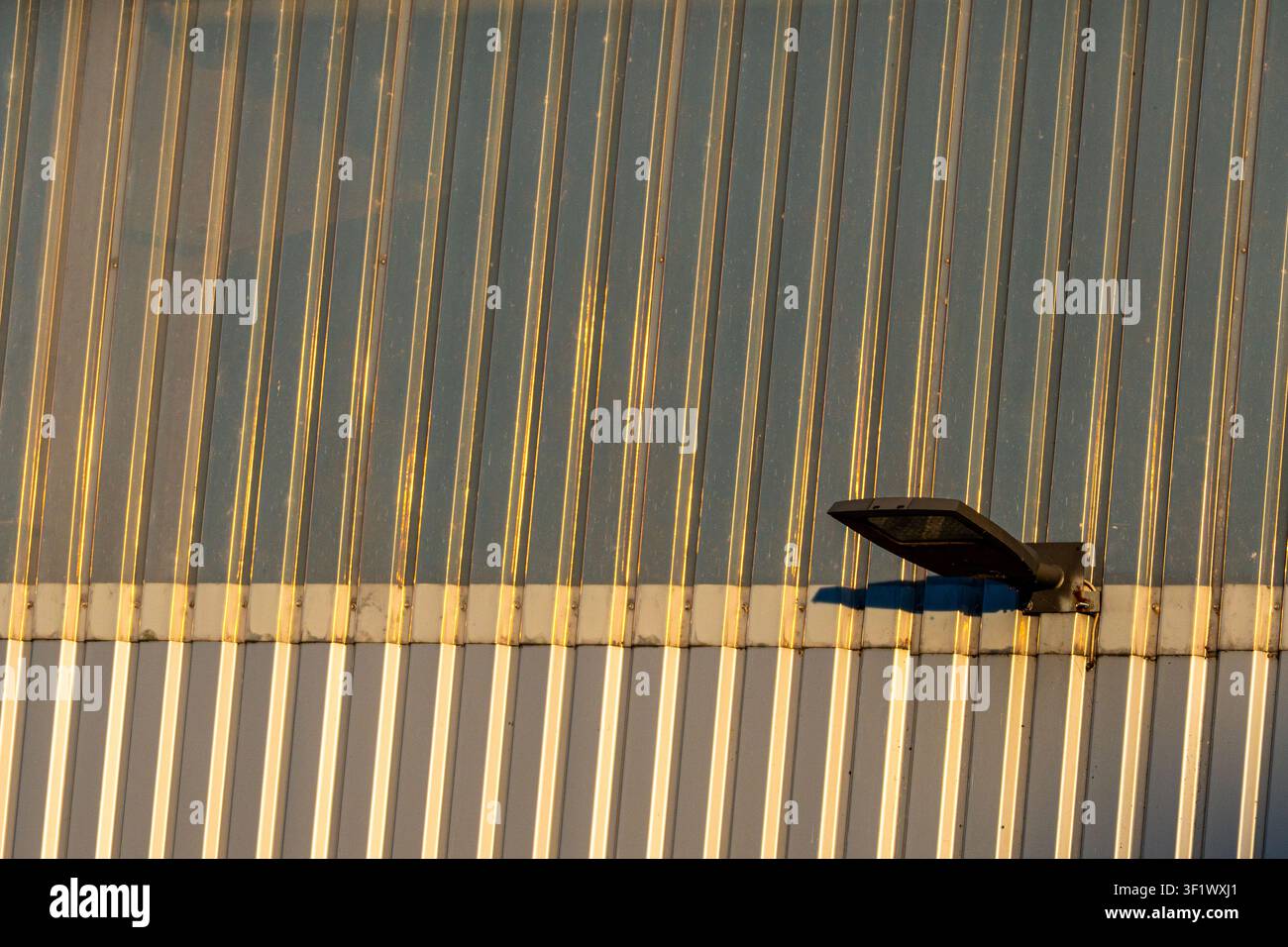 Moderne LED-Flutlichtstrahler an industrieller Wellblechwand Stockfoto