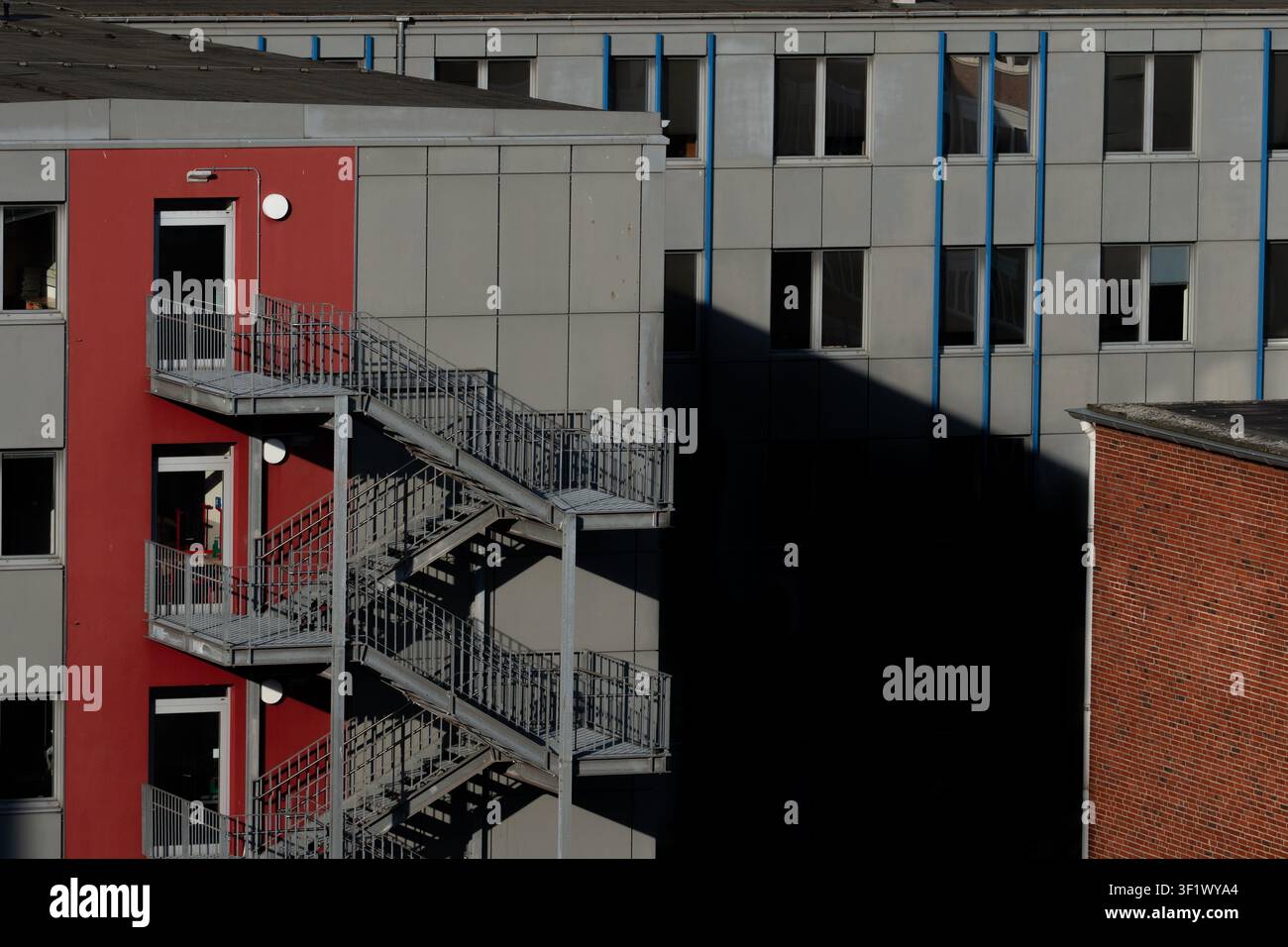 Industrielle äußere Notstahltreppe an roter und grauer Gebäudefassade Stockfoto