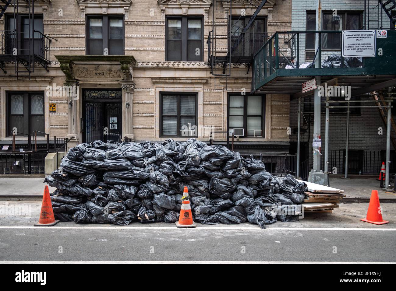 Ein großer Haufen schwarzer Müllsäcke wartet auf die Abholung an einem Bürgersteig in New York City. Stockfoto