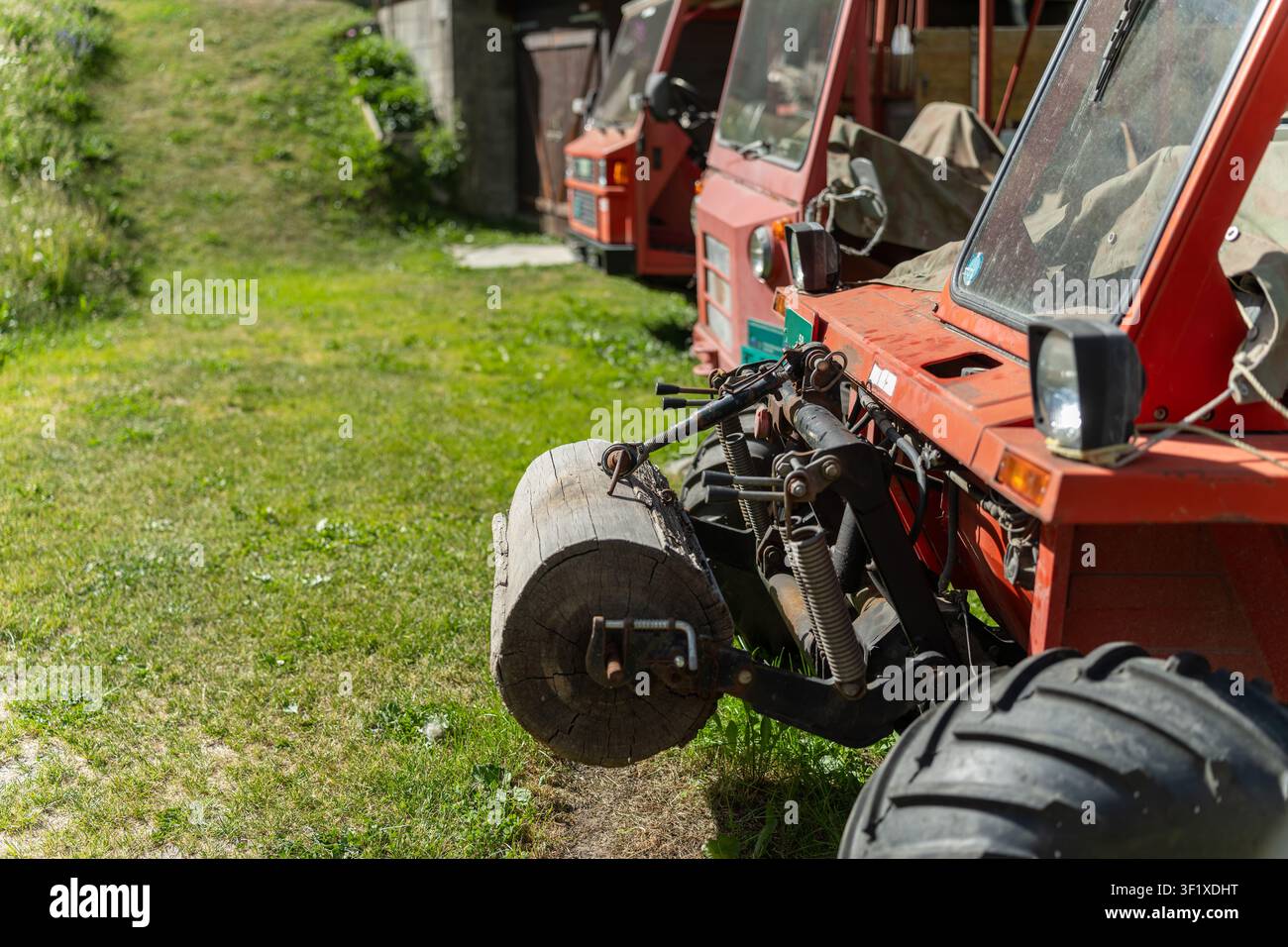 Rote alpine landwirtschaftliche Traktoren, die auf Gras in Zermatt, Schweiz, geparkt sind Stockfoto