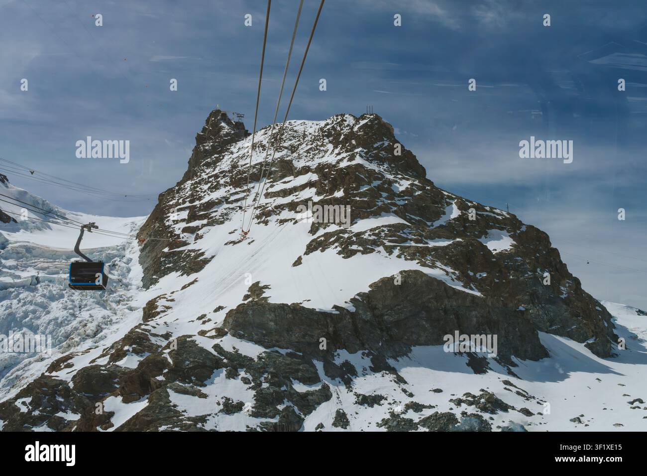 Seilbahn in Zermatt steigt einen schneebedeckten Berg hinauf, mit sichtbarem Gletscher Stockfoto