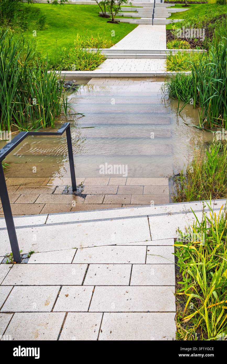 Moderner Gartenweg mit Wasserspiel und Treppen nach starkem Regen Stockfoto