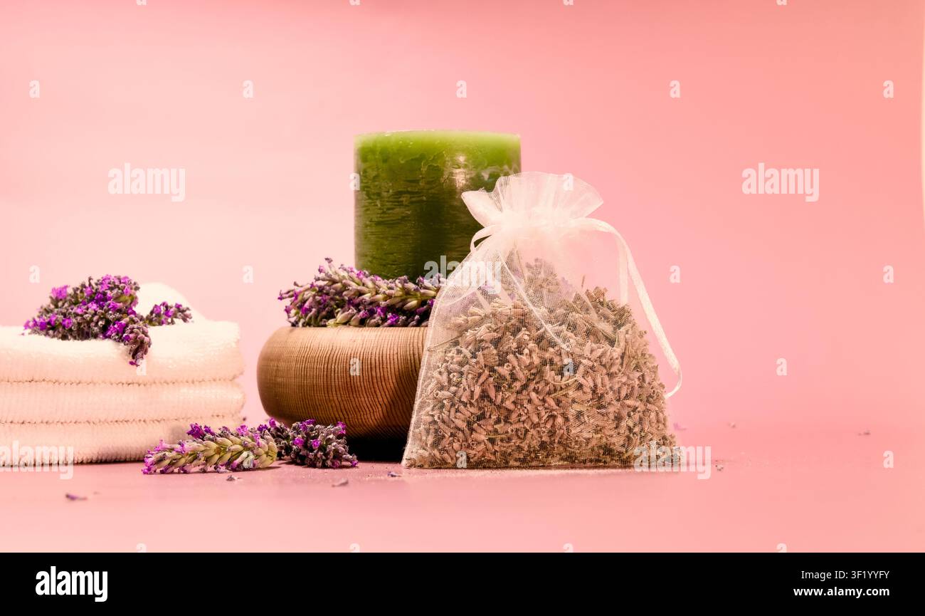 Eine von einem Spa inspirierte Komposition zeigt eine grüne Kerze, umgeben von Lavendel in einer Holzschale, einen Stapel weißer Handtücher Stockfoto