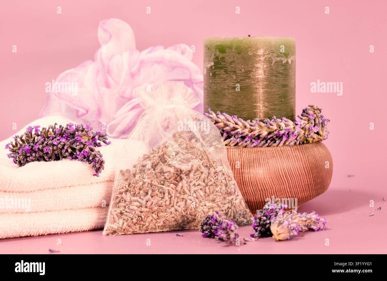 Spa-Essentials-Setup zeigt einen Stapel weißer Handtücher, eine grüne Kerze, eine Holzschale mit Lavendel Stockfoto