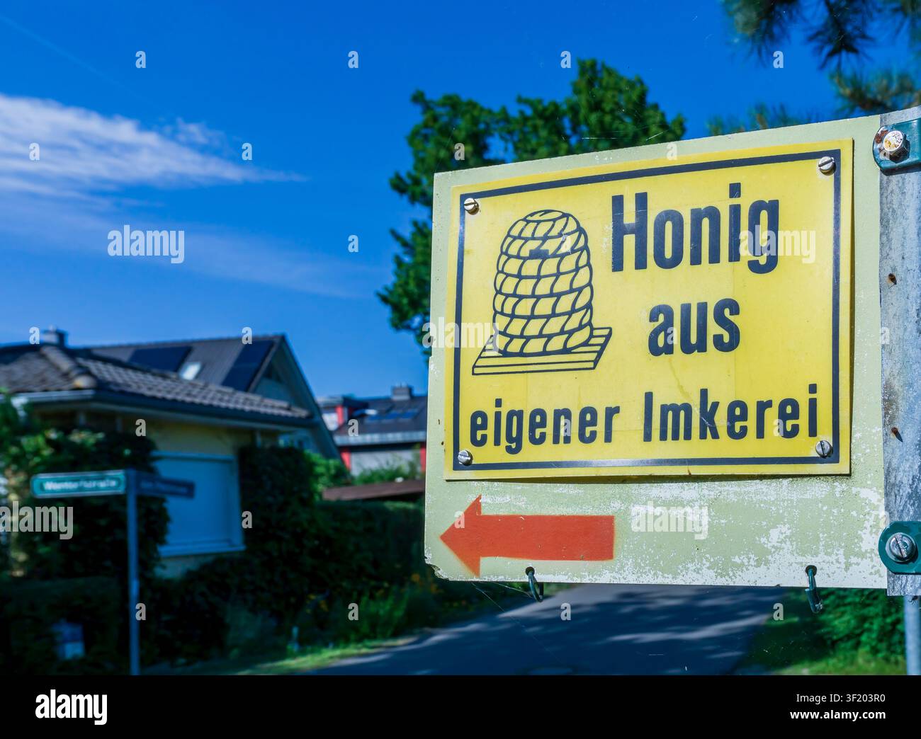 Straßenschild, das lokal produzierten deutschen Honig aus einem privaten Imkerbetrieb in einem ländlichen Wohngebiet bewirbt. Honig, Schild, Imkerei. Stockfoto