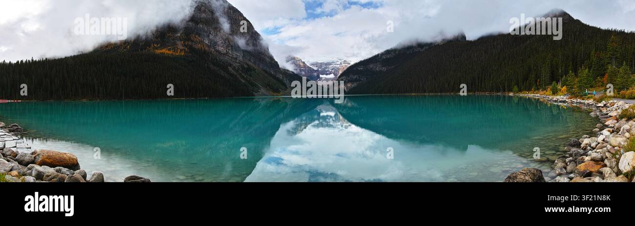 Ein ruhiger Bergsee, der die umliegenden Gipfel und Wolken widerspiegelt. Stockfoto