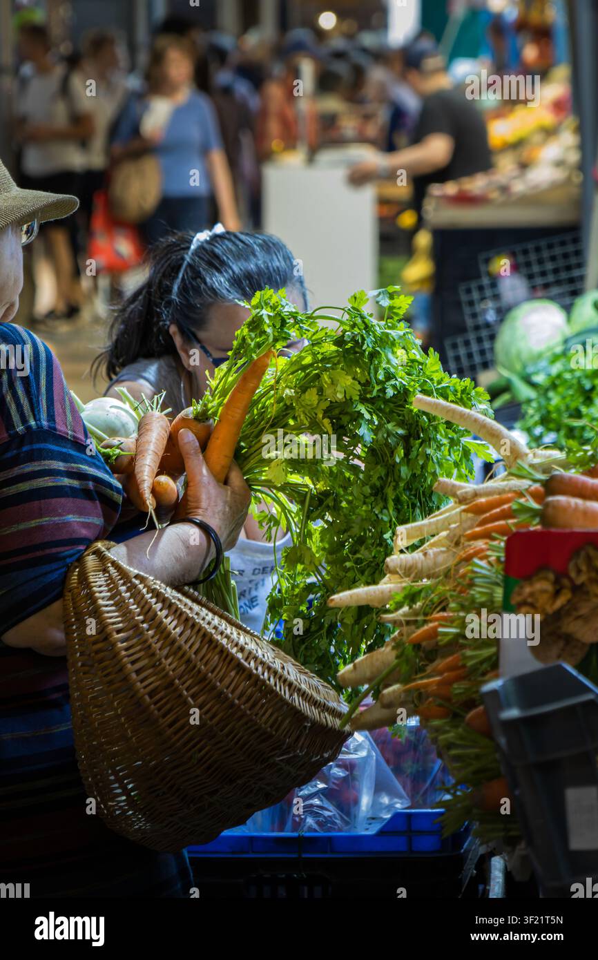 Kunde wählt frische Karotten und Petersilie am Marktstand Stockfoto