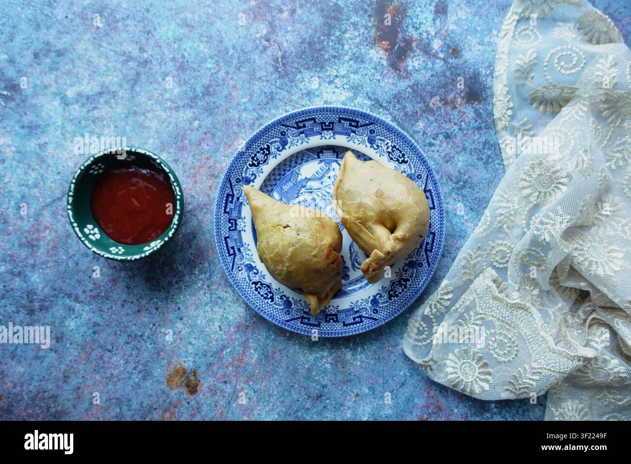 Samosas und Soße auf einem Teller mit einer Tischdecke daneben Stockfoto
